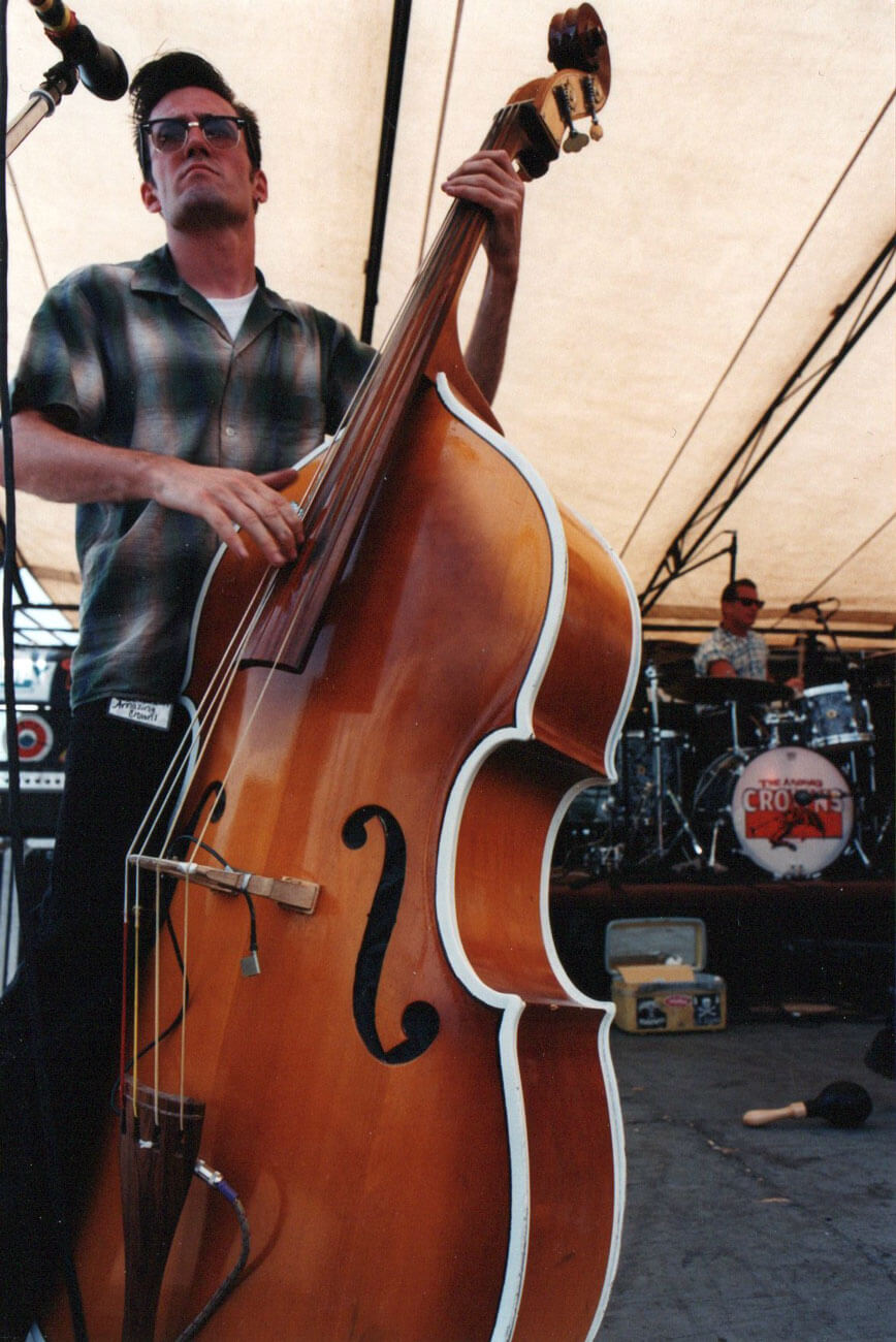 Person playing a double bass on a stage with musical equipment in the background
